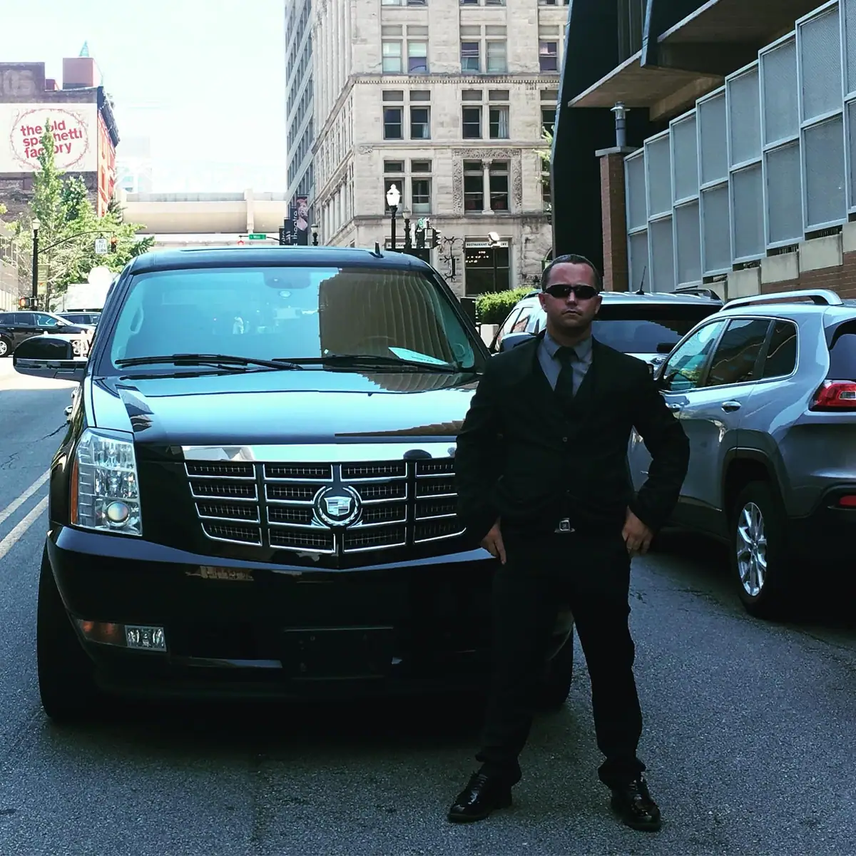 Chauffeur beside a black Cadillac Escalade